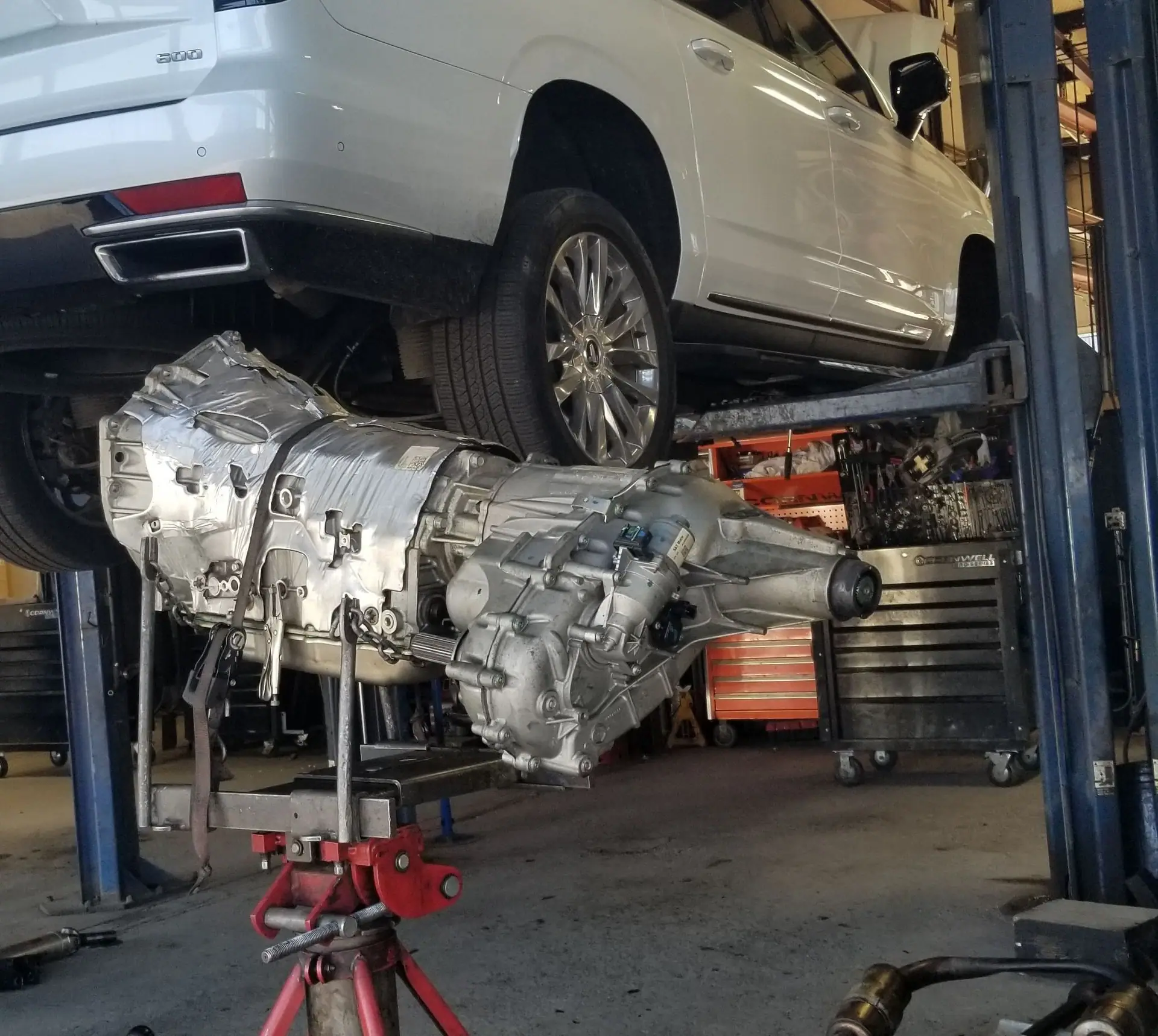 Vehicles up on the lifts inside the J&W shop in Cincinnati, with an engine and a transmission coming out