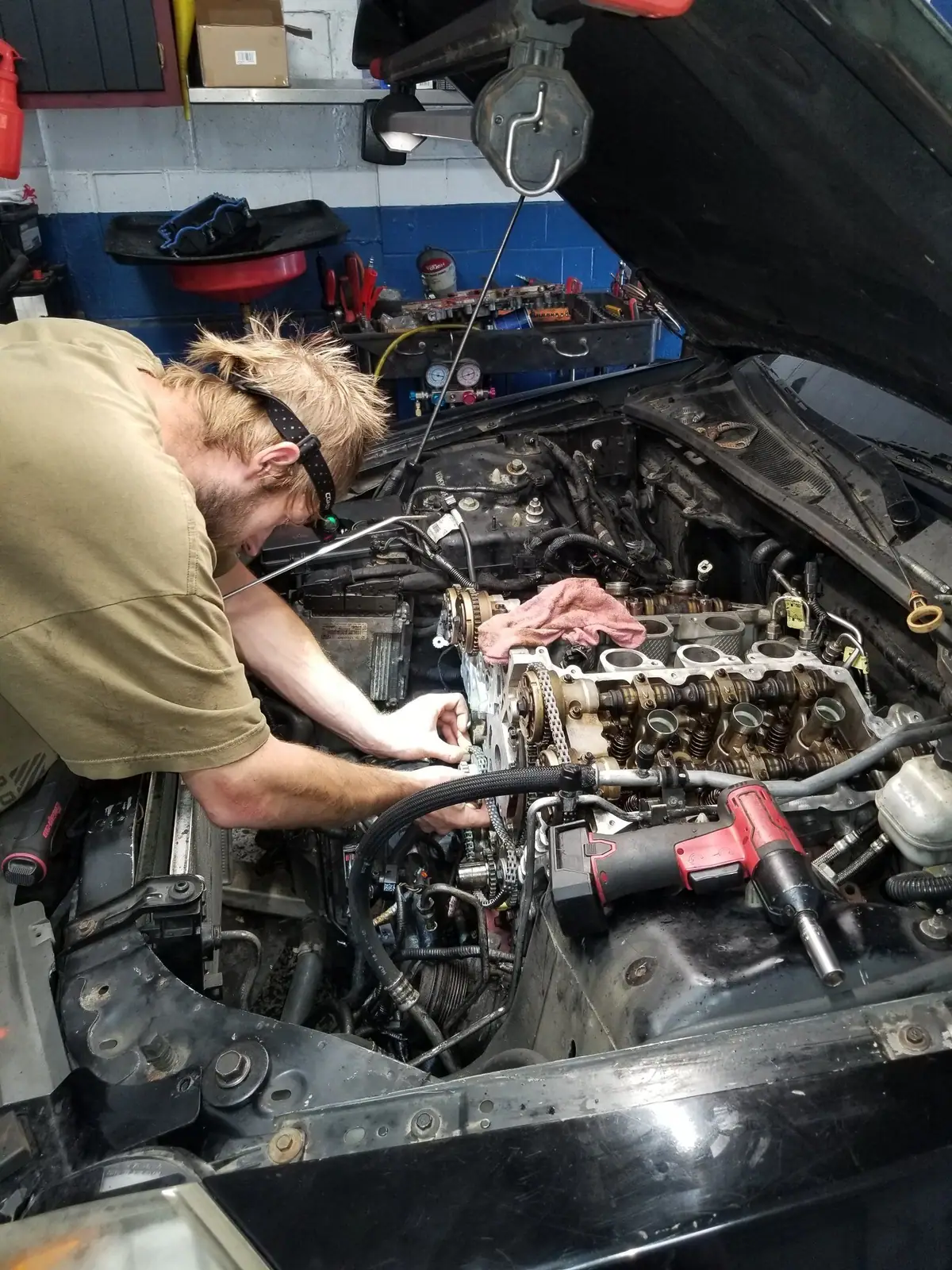 J&W mechanic in a headlamp working on a V6 with the cylinder heads off