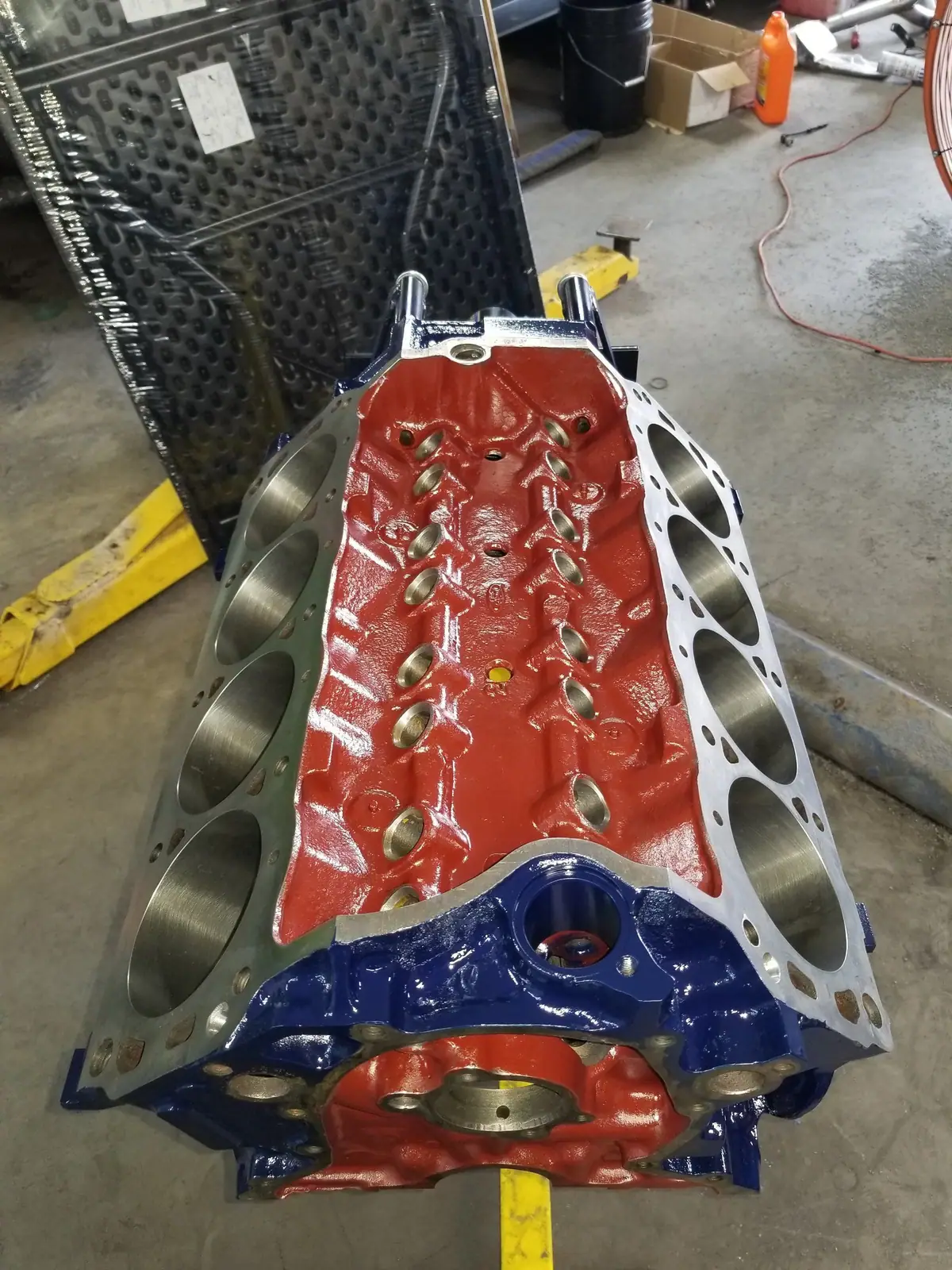 Freshly painted V8 engine block, red with blue ends, on the shop floor