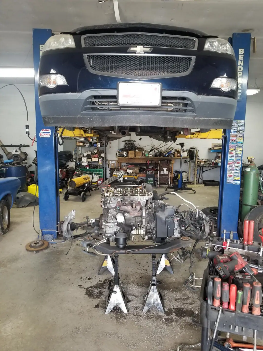 Chevy crossover up on the lift with its engine lowered out onto stands