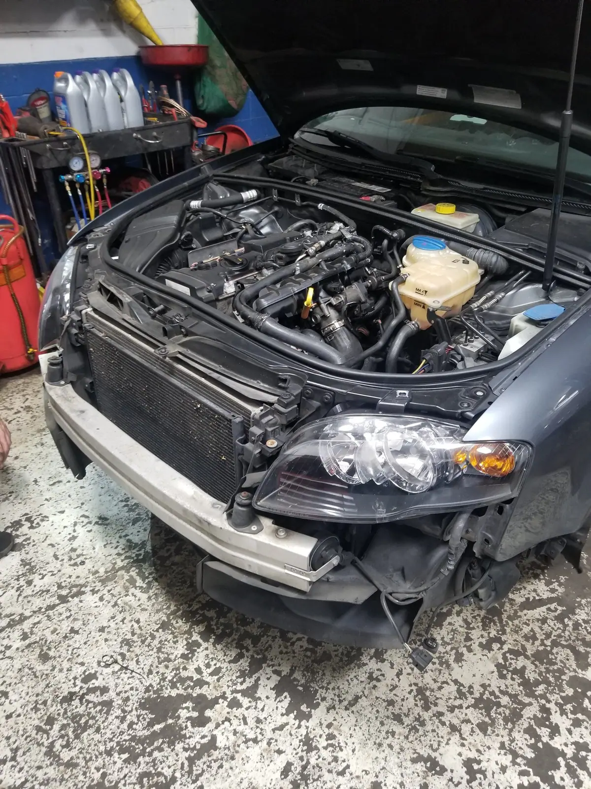 Car in the bay with the front bumper off and the engine bay opened up