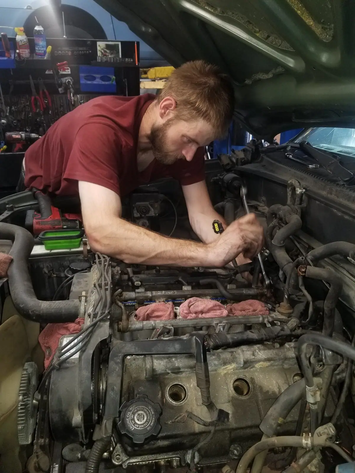 J&W mechanic in a red shirt working on an engine with the heads off